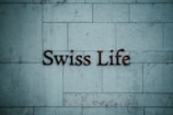 Text reading 'Swiss Life' is mounted on a tiled stone wall with a muted blue-grey hue.