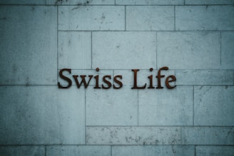 Text reading 'Swiss Life' is mounted on a tiled stone wall with a muted blue-grey hue.