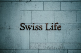 Text reading 'Swiss Life' is mounted on a tiled stone wall with a muted blue-grey hue.
