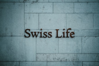 Text reading 'Swiss Life' is mounted on a tiled stone wall with a muted blue-grey hue.