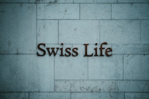Text reading 'Swiss Life' is mounted on a tiled stone wall with a muted blue-grey hue.