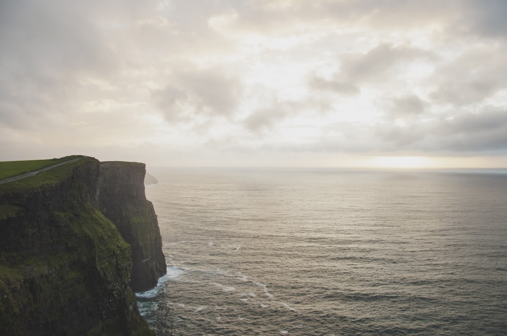 grayscale photo of cliff near sea