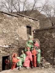 A group of diverse villagers standing together in front of traditional stone houses in Jasses.