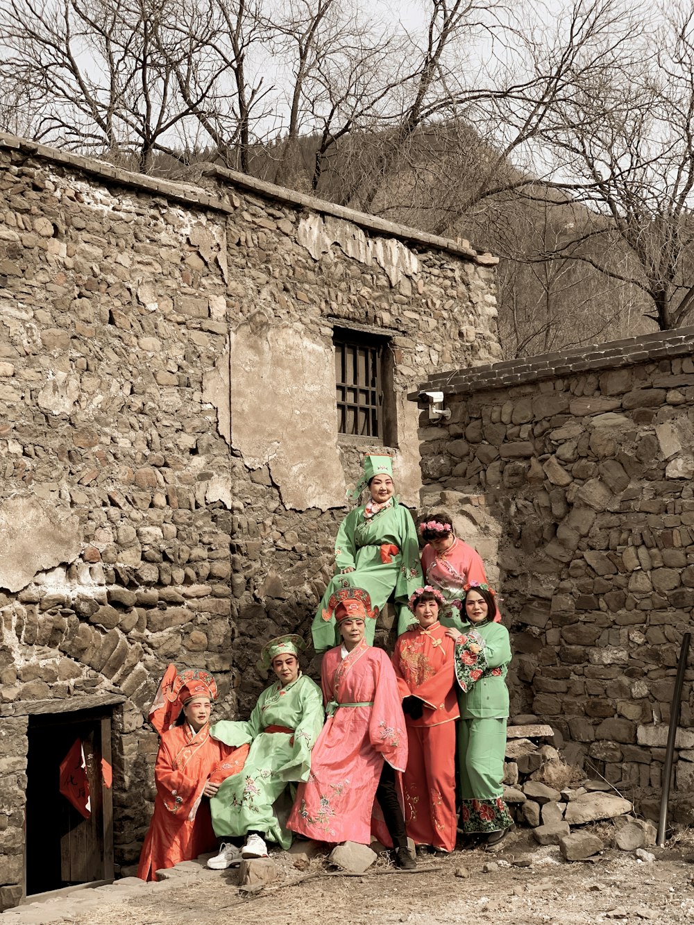 people in green and orange traditional dress standing near brown brick wall during daytime