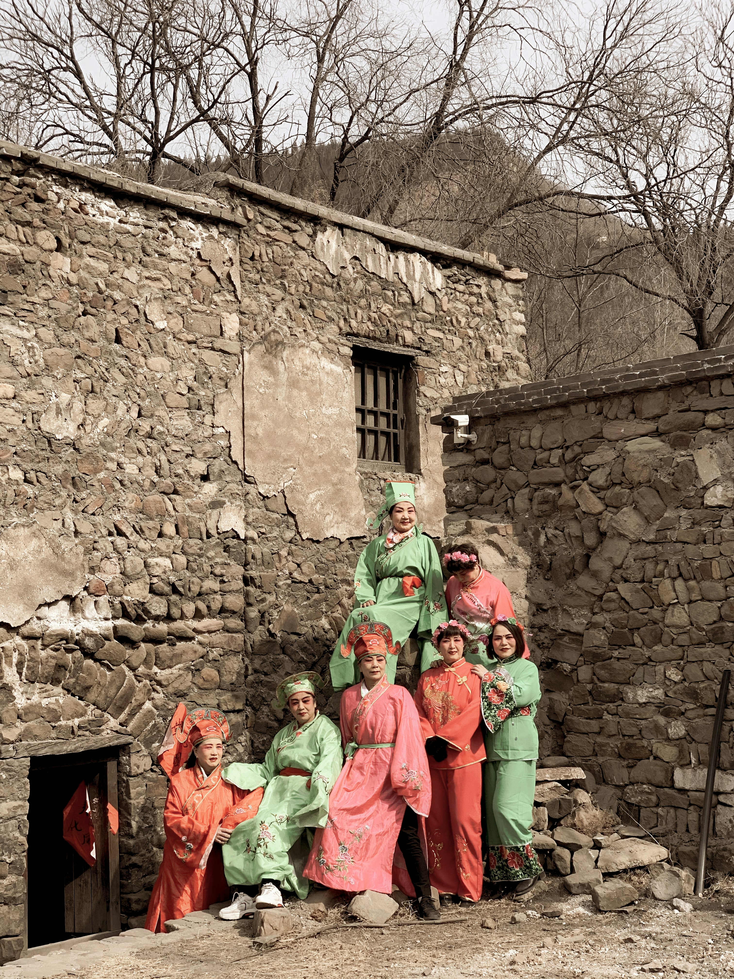 people in green and orange traditional dress standing near brown brick wall during daytime