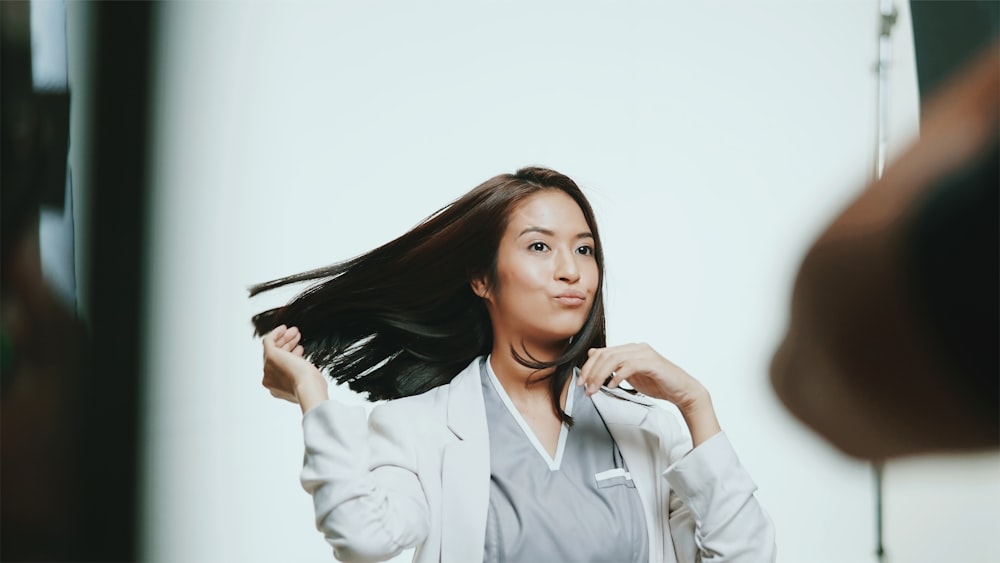 woman in white button up shirt holding her hair