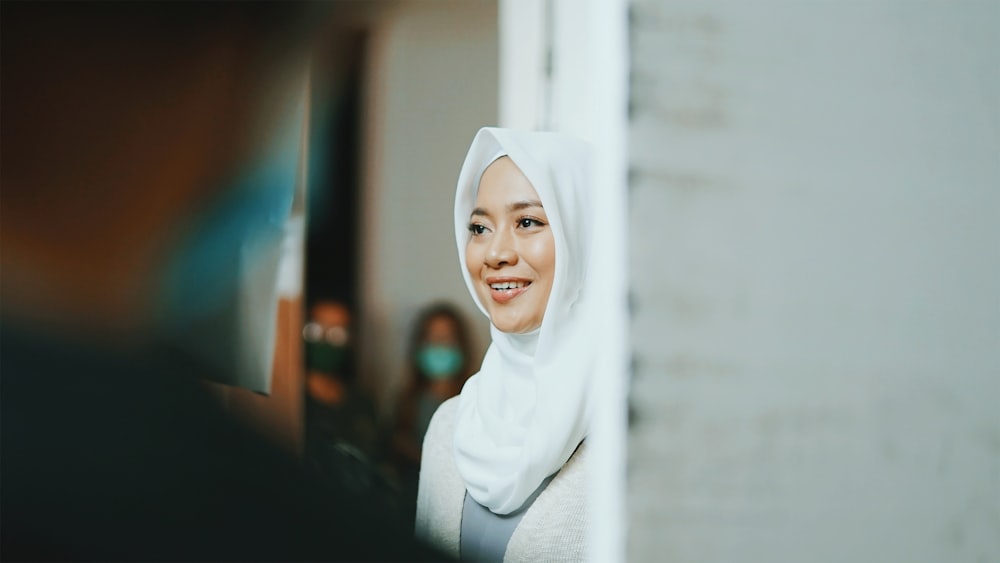 woman in white hijab standing near white wall