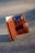 A brown leather wallet standing upright on a textured gray surface. It is open, revealing a blue Visa credit card and some cash tucked inside. The wallet's brand name 'KALIBRADO' is embossed on the leather.