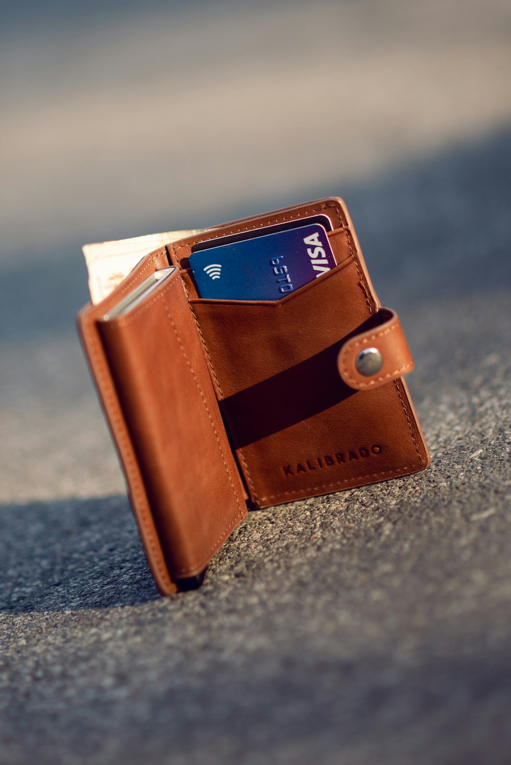 brown leather bifold wallet on gray concrete floor