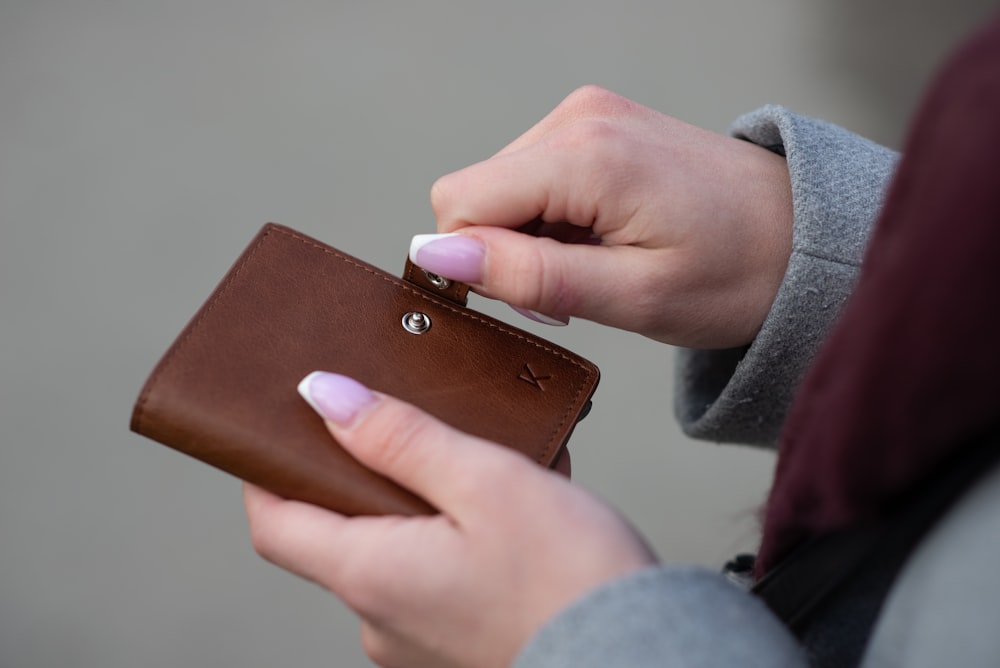 Persona sosteniendo una billetera de cuero marrón