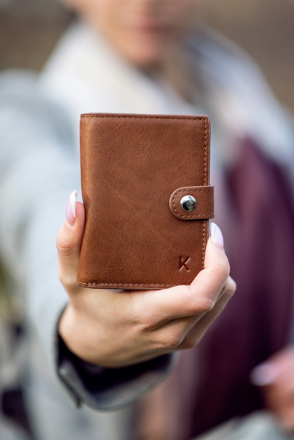 person holding brown leather bifold wallet