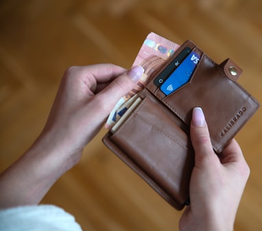 person holding brown leather card wallet