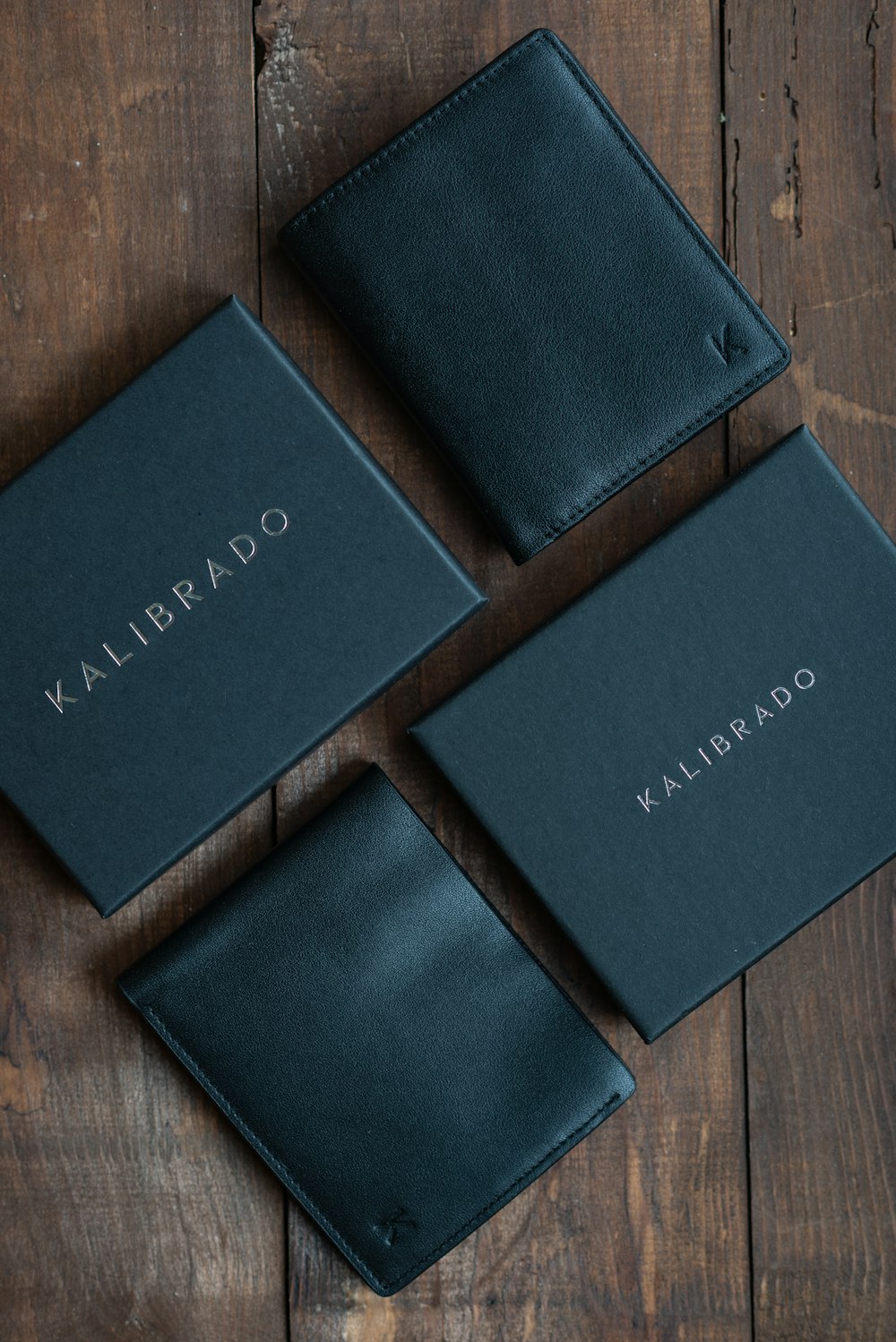 three black wallets sitting on top of a wooden table
