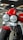 A close-up view of a motorcycle featuring dual round headlights, a prominent red fuel tank, and a sturdy front suspension. The motorcycle has a modern and robust design with a focus on the front wheel and tire. The showroom setting provides a sleek and polished look.