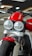 A close-up view of a motorcycle featuring dual round headlights, a prominent red fuel tank, and a sturdy front suspension. The motorcycle has a modern and robust design with a focus on the front wheel and tire. The showroom setting provides a sleek and polished look.