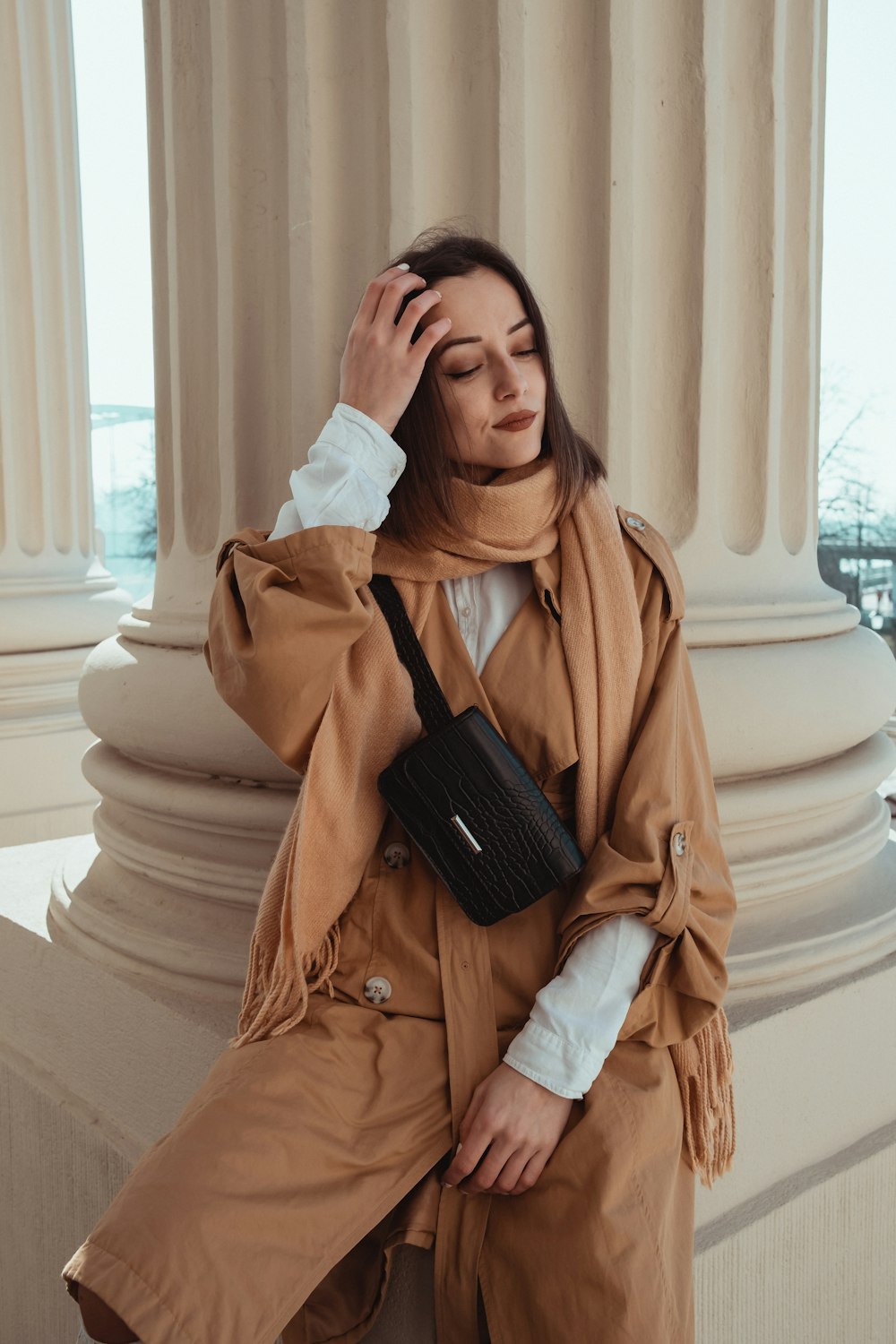 woman in brown coat holding black smartphone