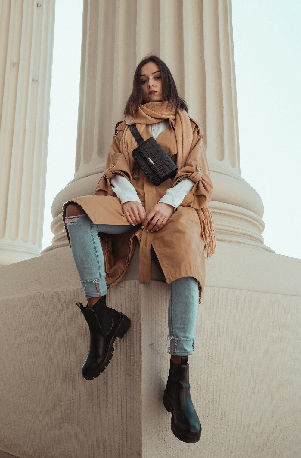 woman in brown leather jacket and blue denim jeans holding black leather bag