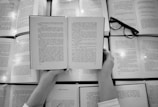 person holding book page with black frame eyeglasses