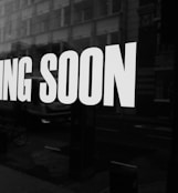 a black and white photo of a sign that says coming soon