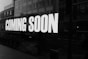 a black and white photo of a sign that says coming soon