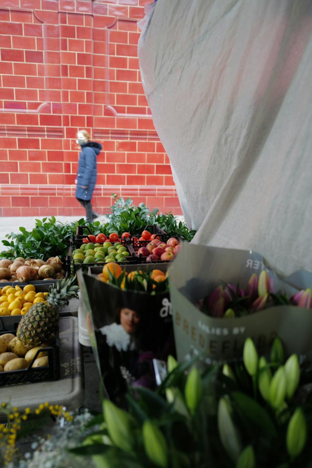 man in blue jacket standing in front of fruit stand