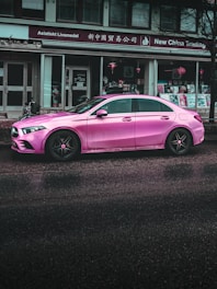 pink porsche 911 parked near white building during daytime