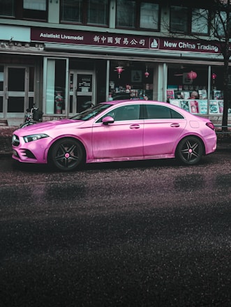 pink porsche 911 parked near white building during daytime