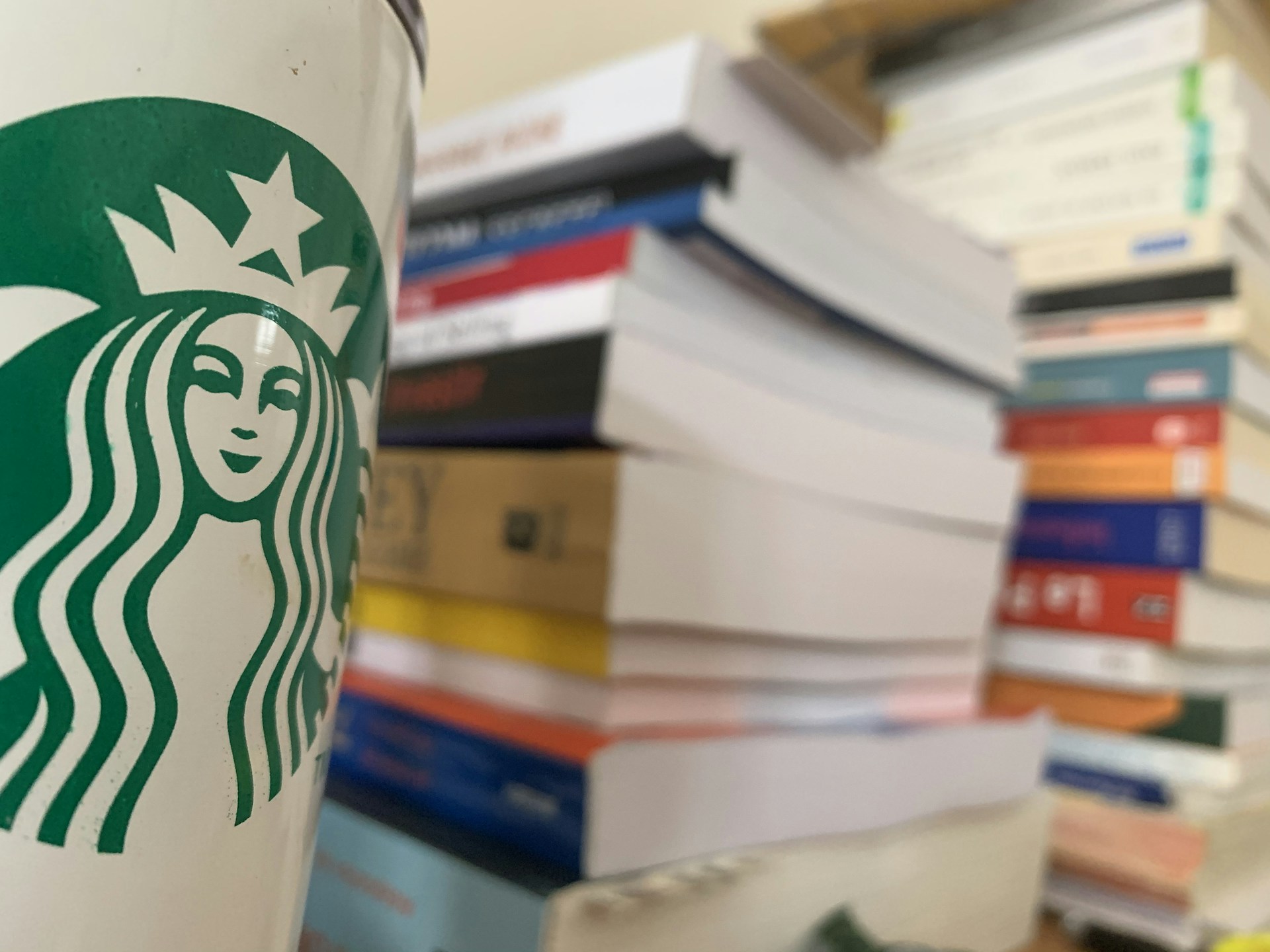 An elegant stack of Marco di Caprio's books arranged on a wooden table beside a steaming cup of espresso, with a blurred background of Roman architecture.