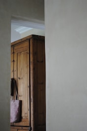 An open wardrobe showcasing hand-finished wood shelves and drawers with soft lighting.