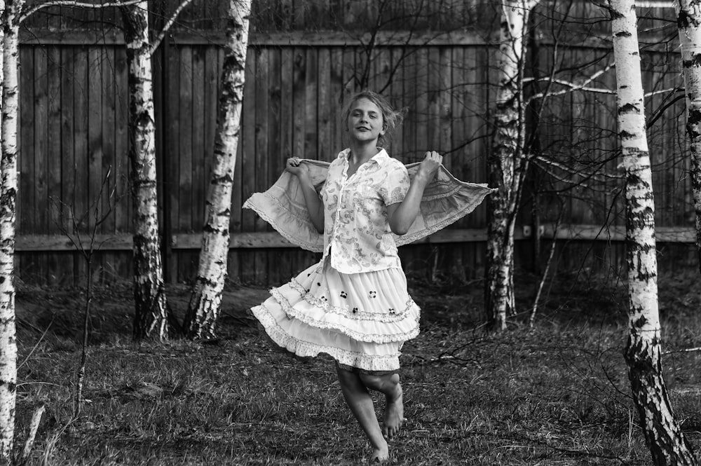 Muchacha en vestido blanco de pie en el campo de hierba