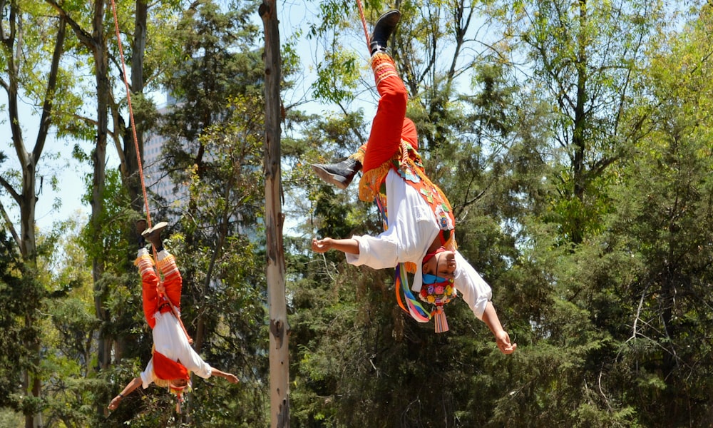 빨간 티셔츠와 흰색 반바지를 입은 남자가 낮에 갈색 나무 기둥에 뛰어든다
