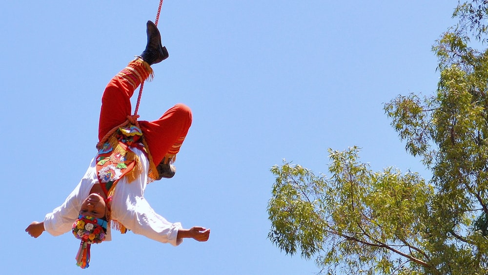 man in red jacket and white pants jumping on mid air under blue sky during daytime