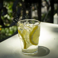 Close-up of clear Fonteviva water pouring into a glass with natural greenery in the background.
