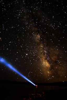 A young student looking up at a starry night sky with a telescope, symbolizing curiosity and space exploration.