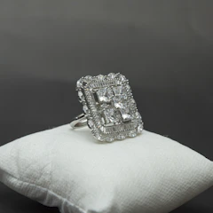 Elegant silver rings with delicate gemstone settings, showcased on a velvet cushion.