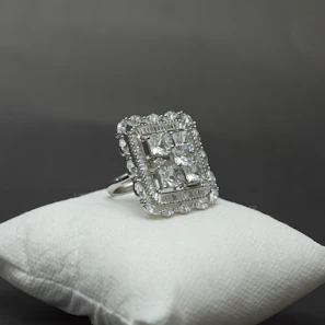 Elegant silver rings with delicate gemstone settings, showcased on a velvet cushion.