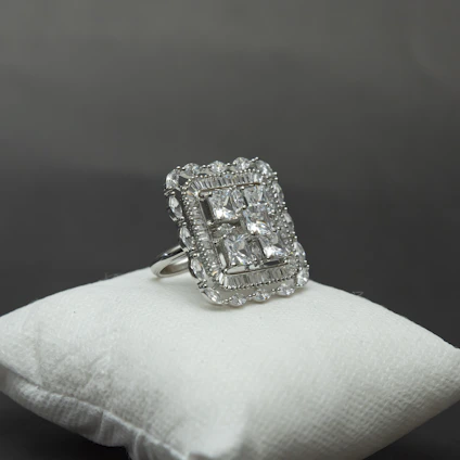 Close-up of a beautifully crafted silver ring resting on a soft velvet cushion.