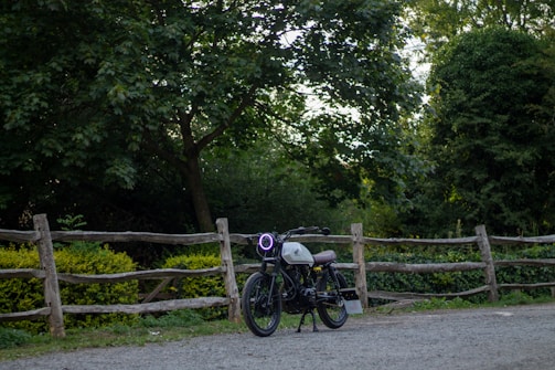 A vintage motorcycle parked beside a rustic wooden fence.