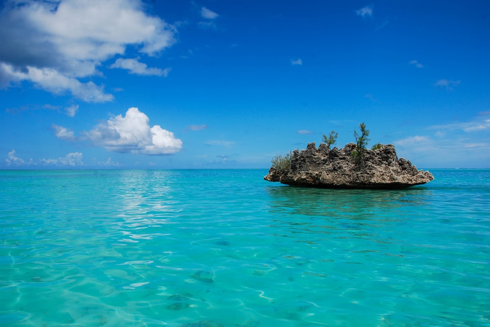 brown rock formation on blue sea under blue sky during daytime