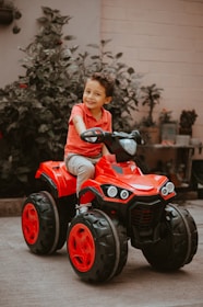 boy in red long sleeve shirt riding red and black atv