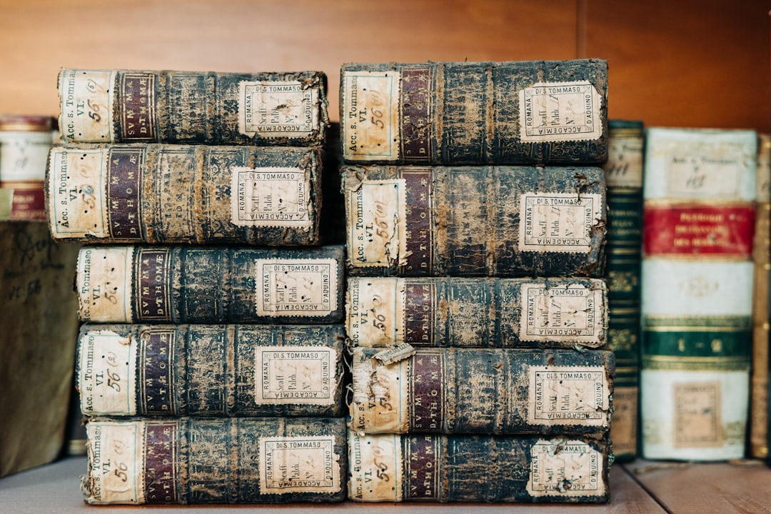white and black labeled plastic packs, A stack of antique books on a shelf