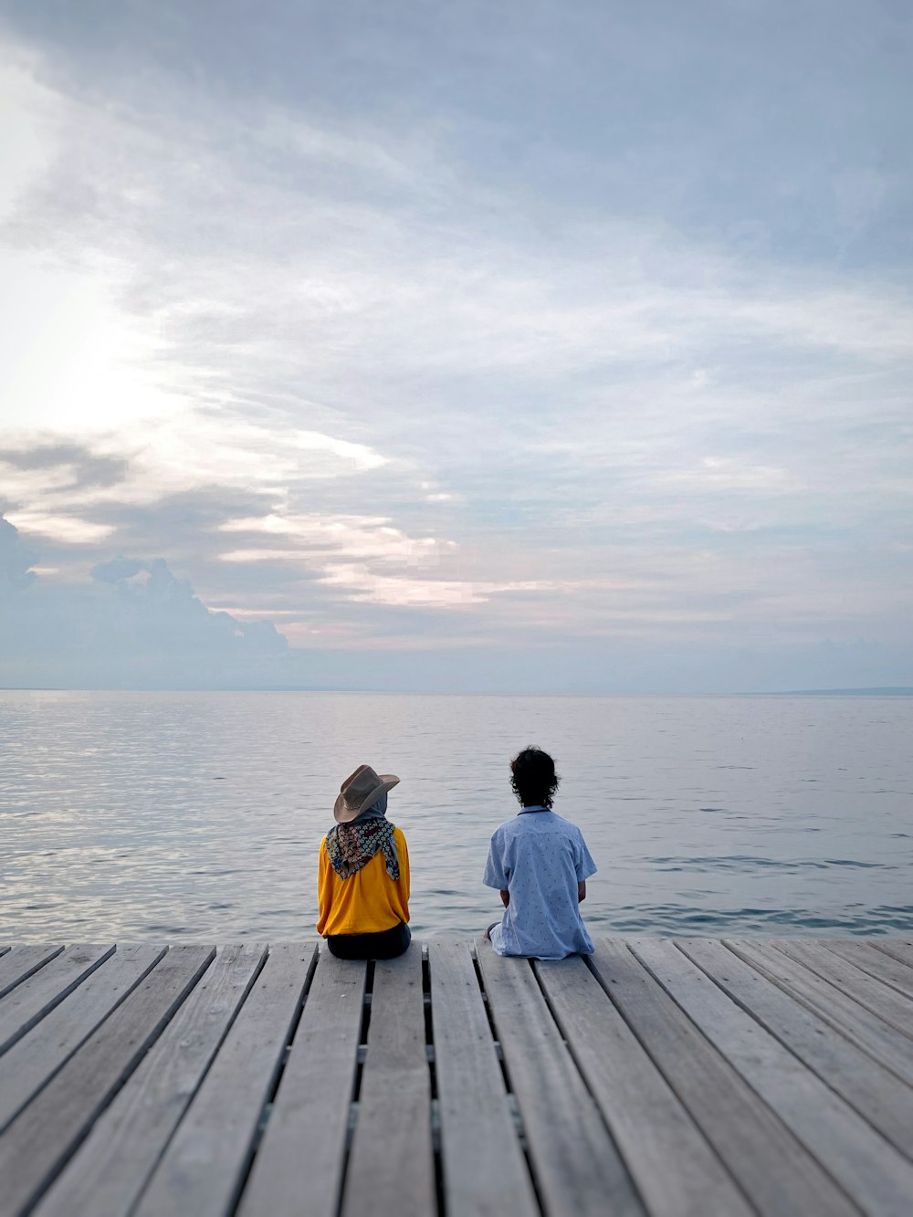 woman in yellow jacket sitting on wooden dock during daytime