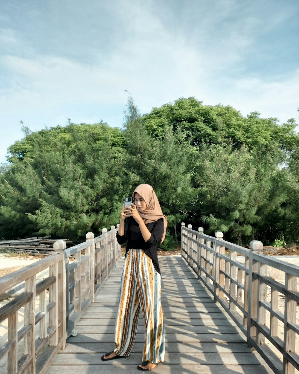 woman in black dress standing on wooden bridge during daytime