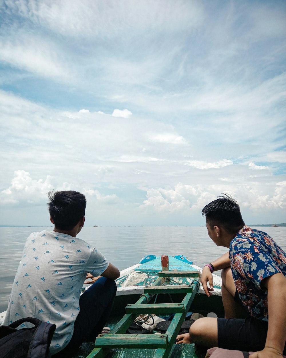 man in gray shirt sitting on green boat during daytime