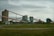 An industrial facility with multiple large, connected structures and conveyor belts spread across a grassy area under an overcast sky.