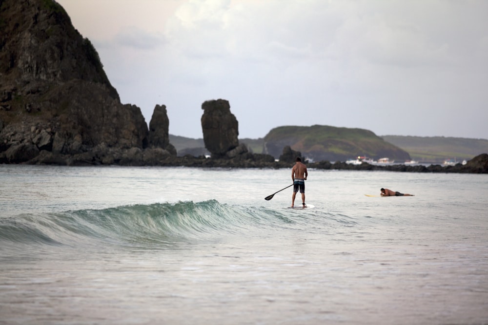 man in black shorts standing on white surfboard on sea during daytime