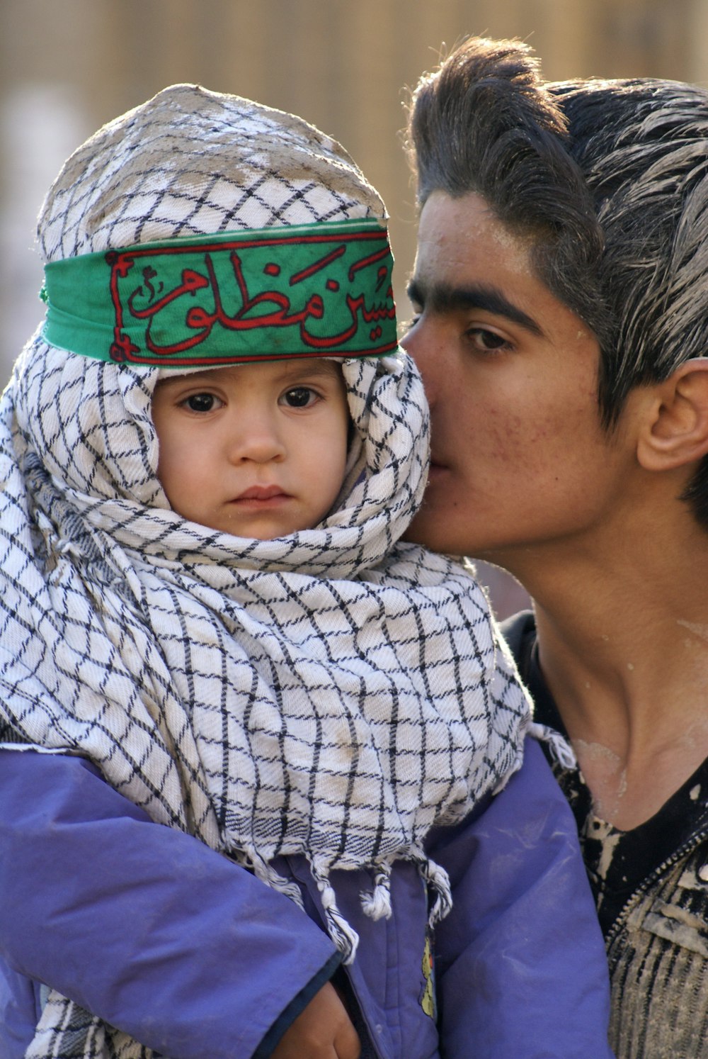 man in white and black checkered dress shirt carrying baby in white and black checkered dress