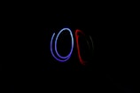 Curved lines of blue and red light create abstract shapes against a black background, suggesting movement or light painting.