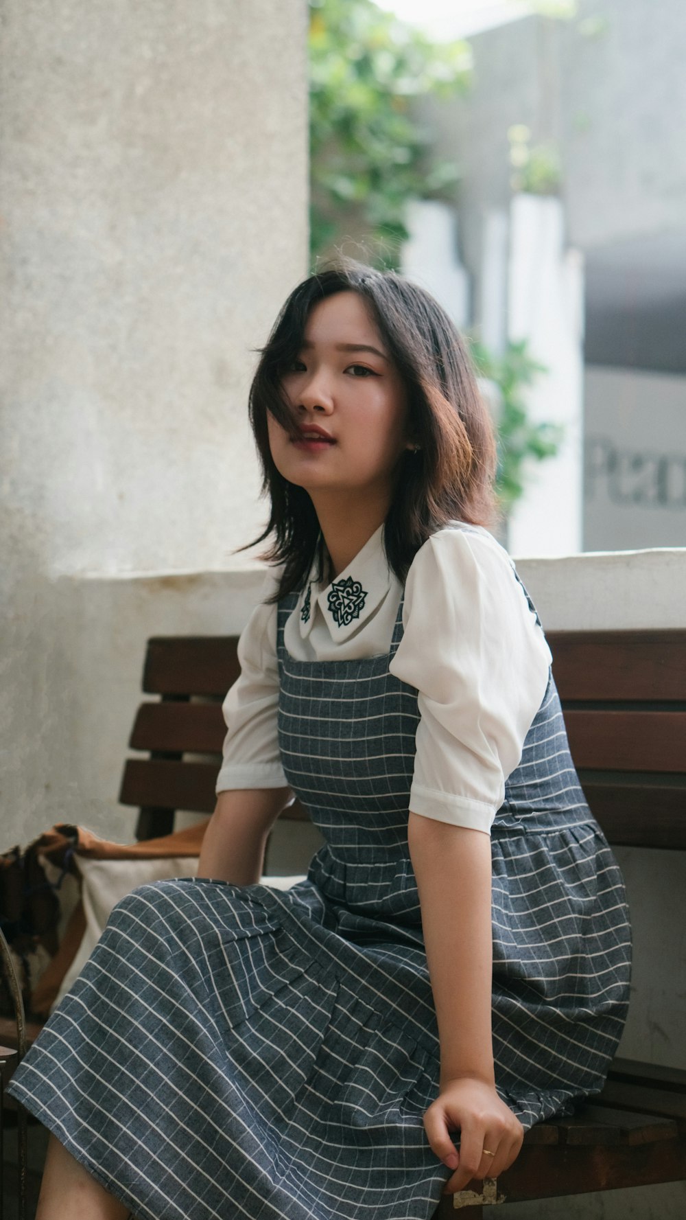 woman in white and black stripe dress sitting on brown wooden bench