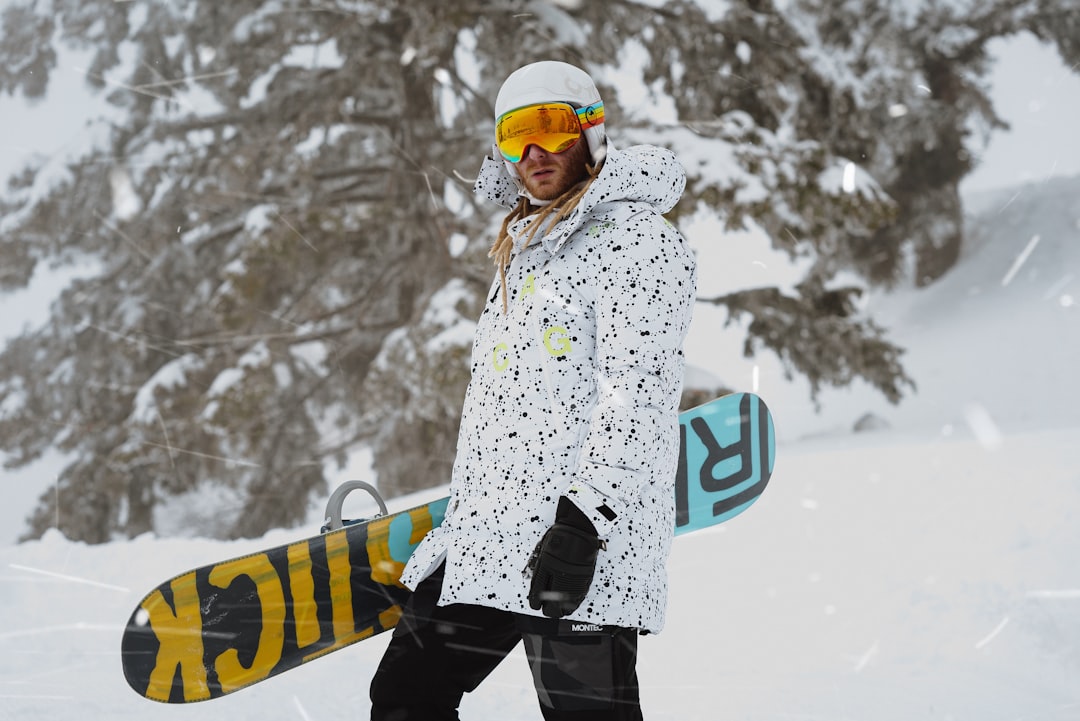 woman in white and black floral coat and black pants standing on snow covered ground during